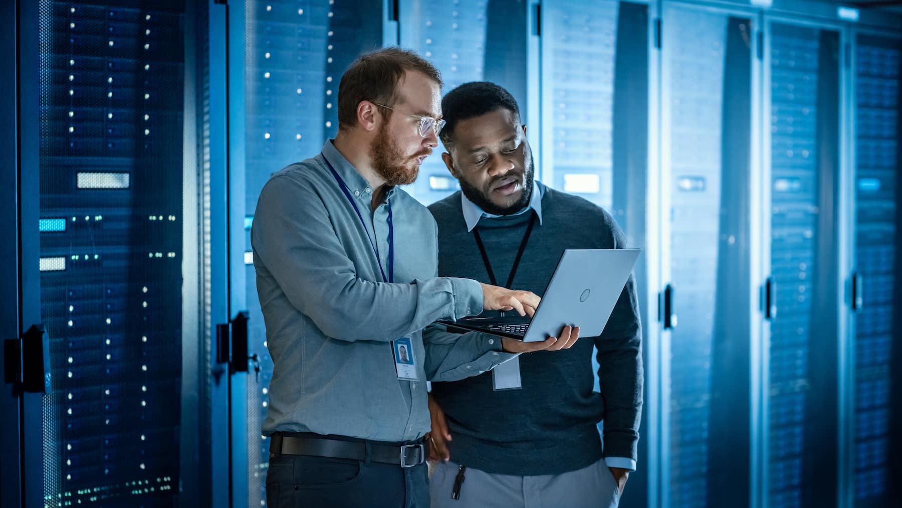 IT professionals in a data center server room with a laptop